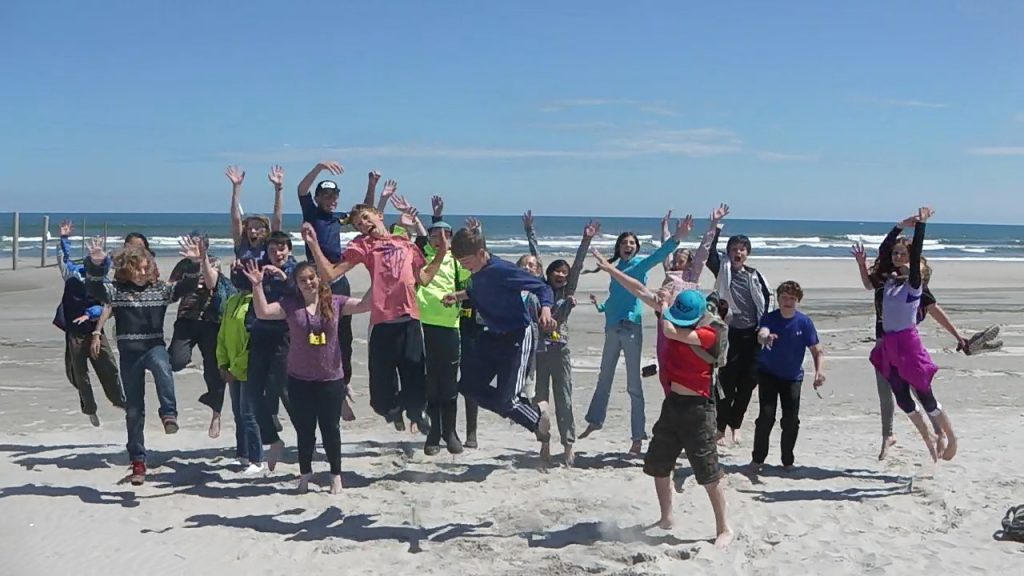 RVCS Students jumping in air during a service learning to the the Delaware Bay